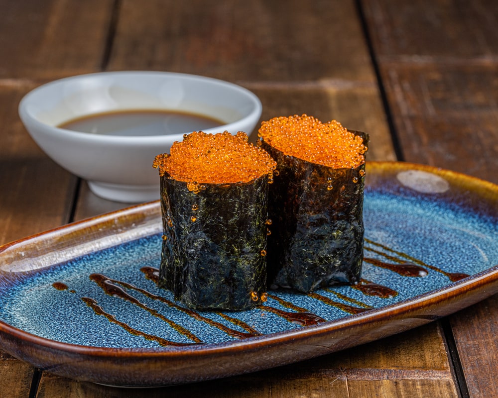 Gunkan brillant garni d'œufs de poissons volants tobiko éclatants, entouré d'une bande d'algue nori, sur un lit de riz vinaigré.