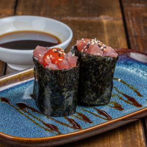 Gunkan garni de thon épicé, entouré d'une bande d'algue nori, sur un lit de riz vinaigré.