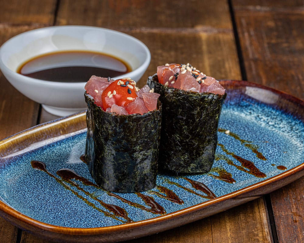 Gunkan garni de thon épicé, entouré d'une bande d'algue nori, sur un lit de riz vinaigré.