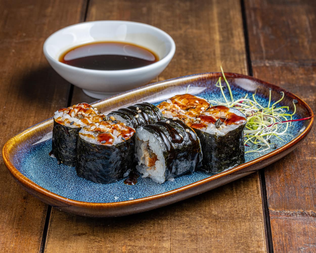 Maki garni d'anguille grillée, présenté de manière élégante avec une texture riche et une saveur fumée distinctive.