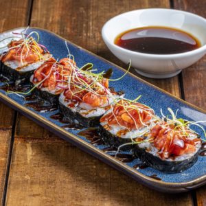Maki lumineux à la teinte orange, garni de saumon frais et enveloppé d'une fine couche de riz vinaigré.