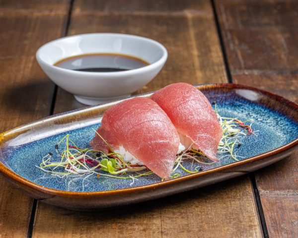 Nigiri élégamment façonné, couronné d'une tranche de thon rouge frais, offrant une saveur profonde et riche sur un lit de riz vinaigré.