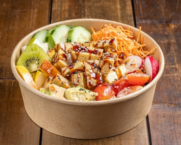 Poké bowl végétarien garni de morceaux de tofu tendres et d'une sélection de légumes frais, présenté dans un bol.