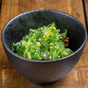 Salade d'algue wakame présentée dans un bol noir.