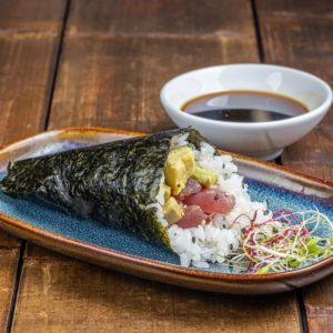 Temaki en forme de cône contenant du thon frais et des tranches d'avocat, enveloppé dans une feuille de nori.