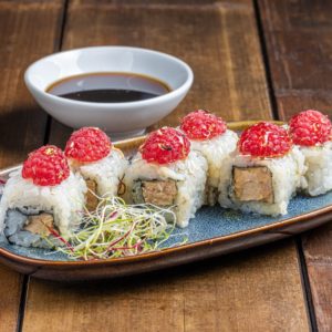 California roll 'French Touch' de 6 pièces, garni de foie gras riche, nappé de miel sucré et agrémenté de notes fruitées de framboise, présenté de manière élégante pour une combinaison gastronomique unique.