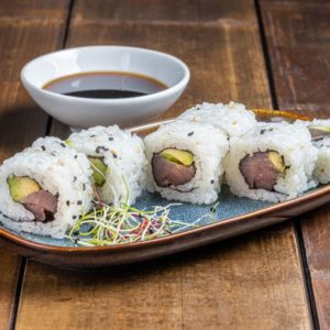 "California roll garni de thon frais et tranches d'avocat crémeux, présenté de manière élégante pour une combinaison savoureuse et équilibrée.