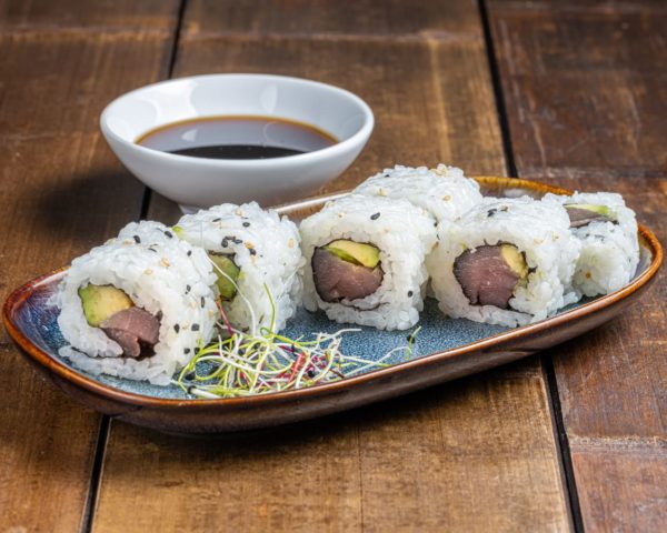 "California roll garni de thon frais et tranches d'avocat crémeux, présenté de manière élégante pour une combinaison savoureuse et équilibrée.